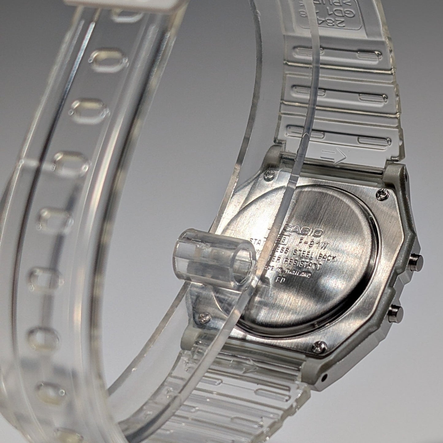Close-up of a Casio watch with a clear strap on a gray background