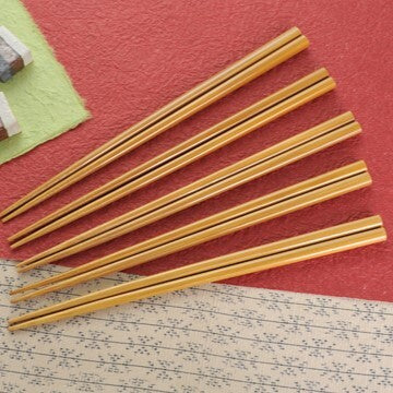 Set of wooden chopsticks on a textured surface with a red background