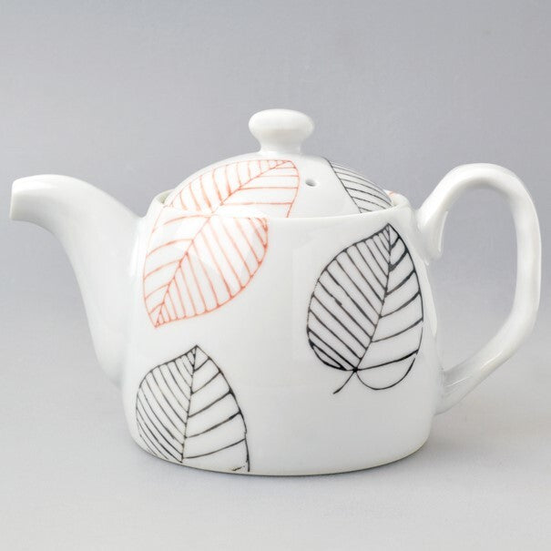 White teapot with leaf patterns on a gray background