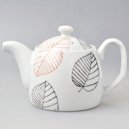 White teapot with leaf patterns on a gray background