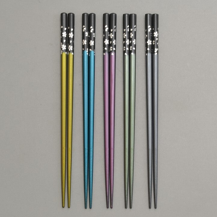 Set of five colorful chopsticks with floral patterns on a gray background