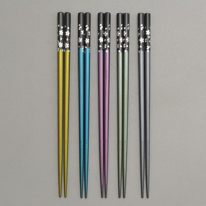 Set of five colorful chopsticks with floral patterns on a gray background