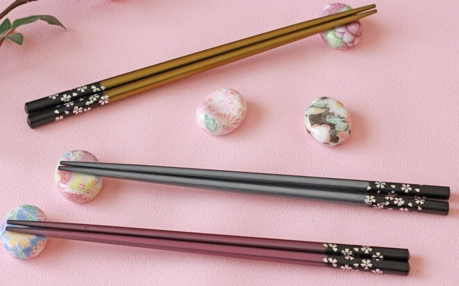 Set of black chopsticks with floral patterns on a pink background
