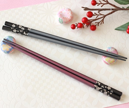 Set of black and pink chopsticks on a textured white surface with decorative elements.