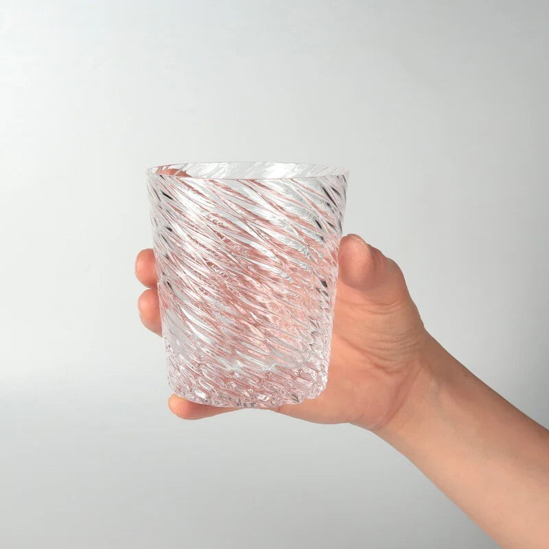 Hand holding a textured glass vase against a plain background