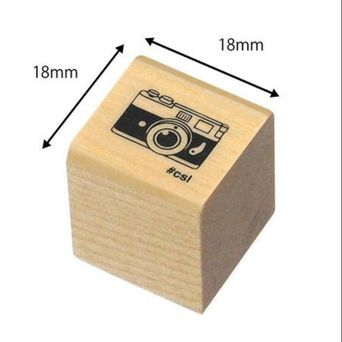 Wooden stamp with camera design and dimensions labeled on a white background