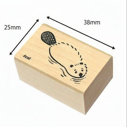 Wooden stamp block with a design of a bear holding a balloon, dimensions indicated, on a white background.