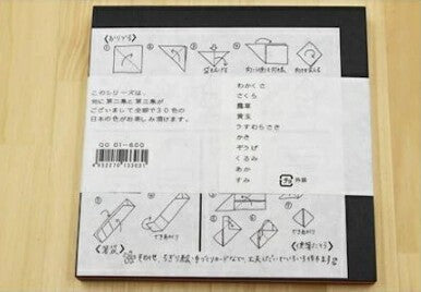A Japanese origami instruction booklet for folding a paper crane, displayed on a light wood background.