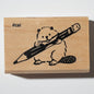 Wooden stamp with beaver chewing a pencil.