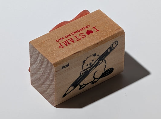 Wooden stamp with beaver chewing a pencil.