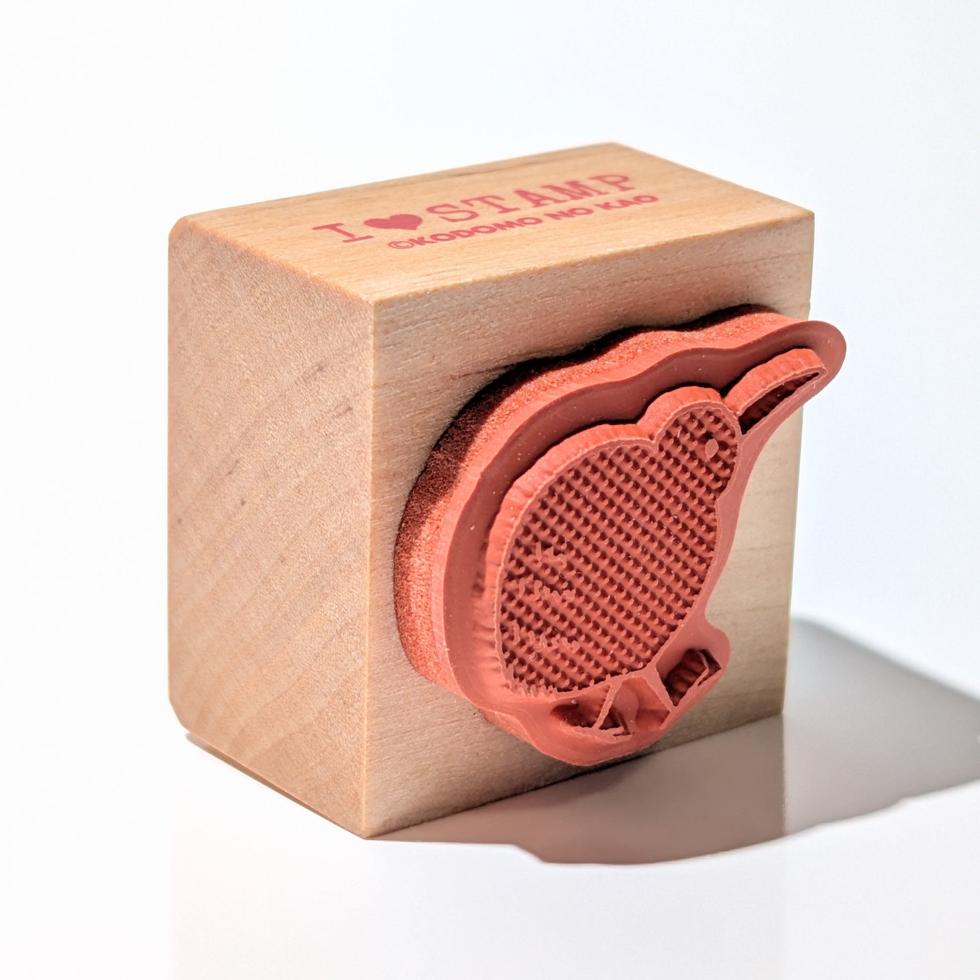 Wooden block with a red leaf-shaped stamp on a white background