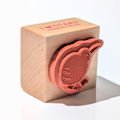 Wooden block with a red leaf-shaped stamp on a white background