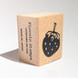 Wooden stamp block with strawberry design and 'Piccolo Stamps' branding on a light gray background