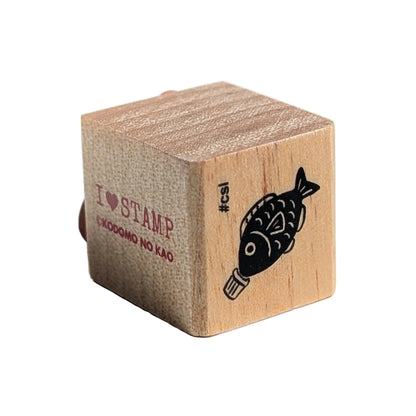 Wooden stamp block with a fish design and text on a white background