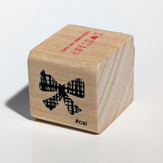 Wooden block with a bow design and text on a light gray background