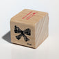 Wooden block with a bow design and text on a light gray background