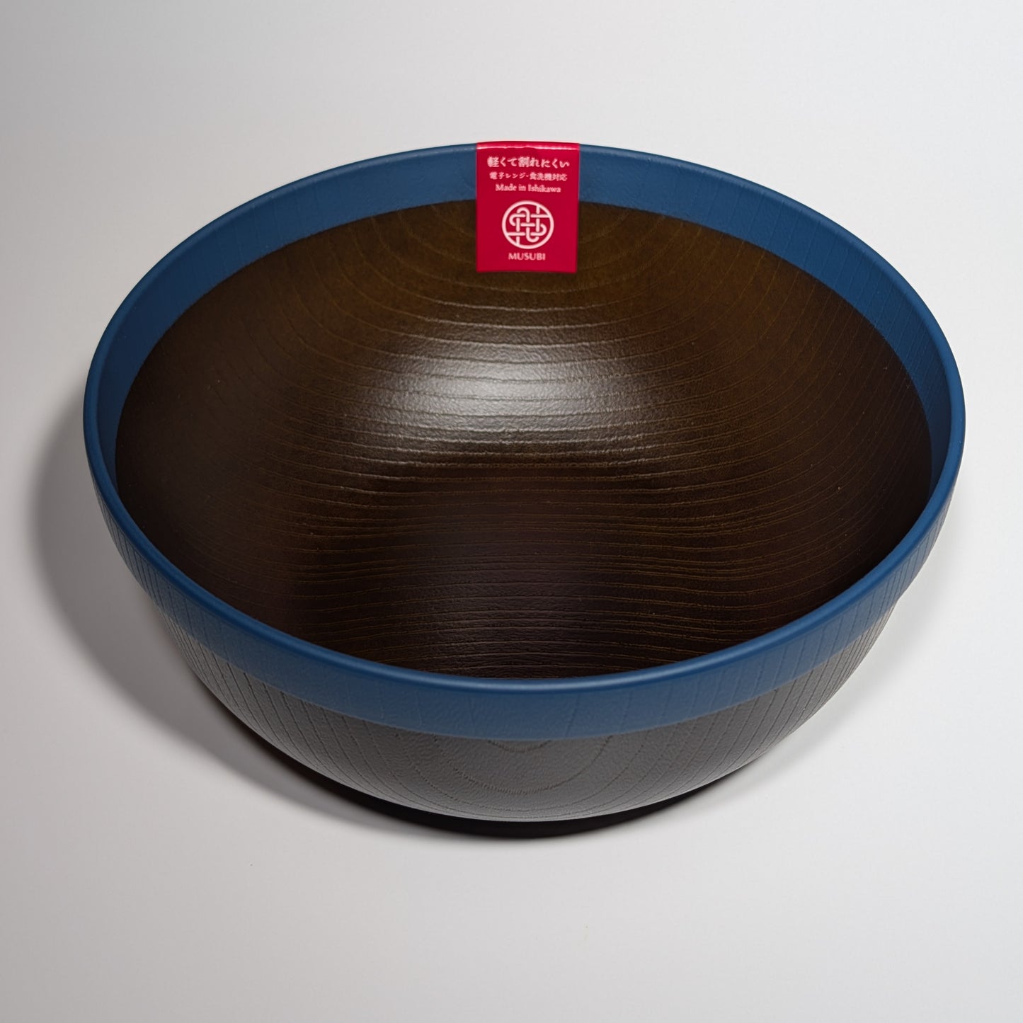 Wooden bowl with a blue rim and a red label on a light gray background