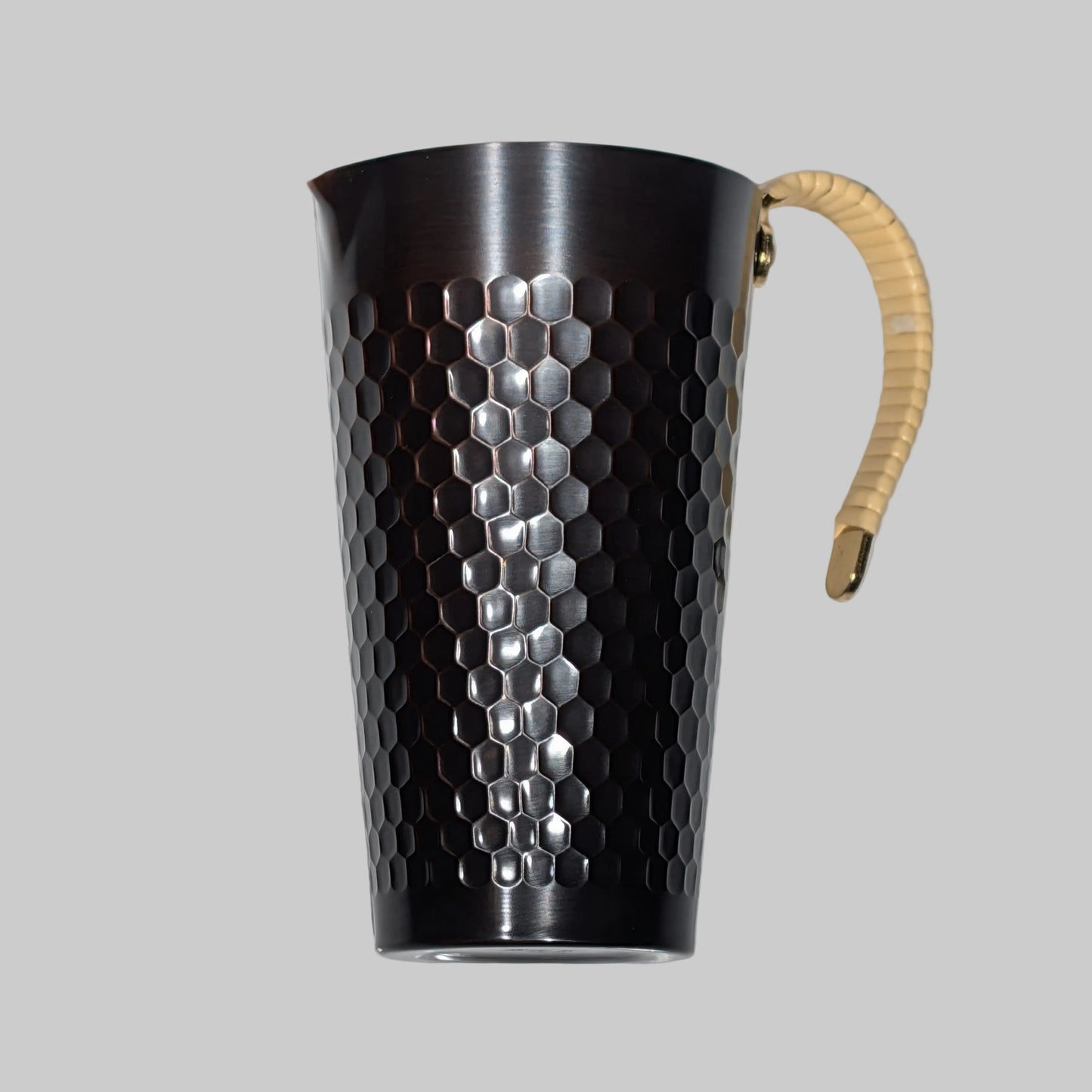 Metal pitcher with honeycomb pattern and wooden handle on a white background