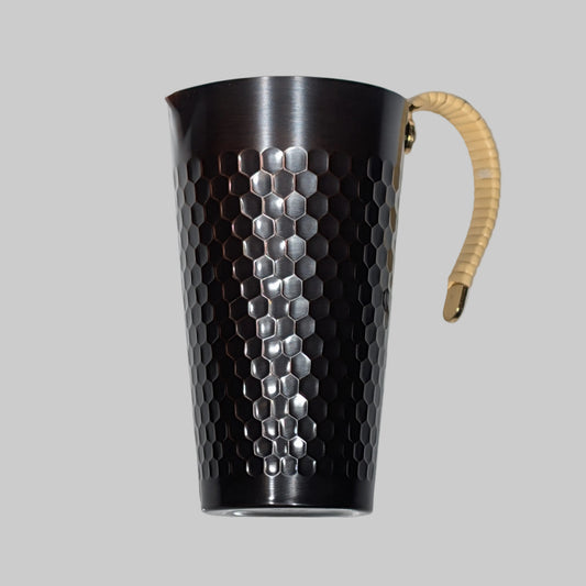Metal pitcher with honeycomb pattern and wooden handle on a white background
