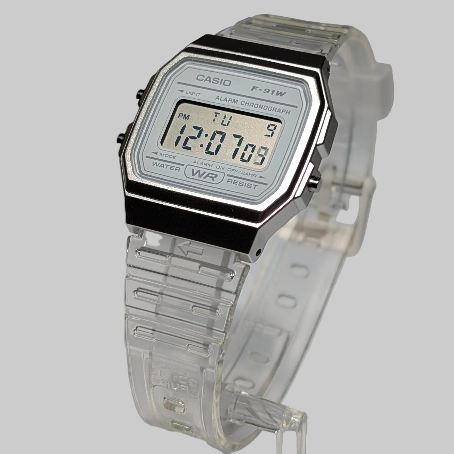Digital watch with clear strap and Casio branding on a gray background